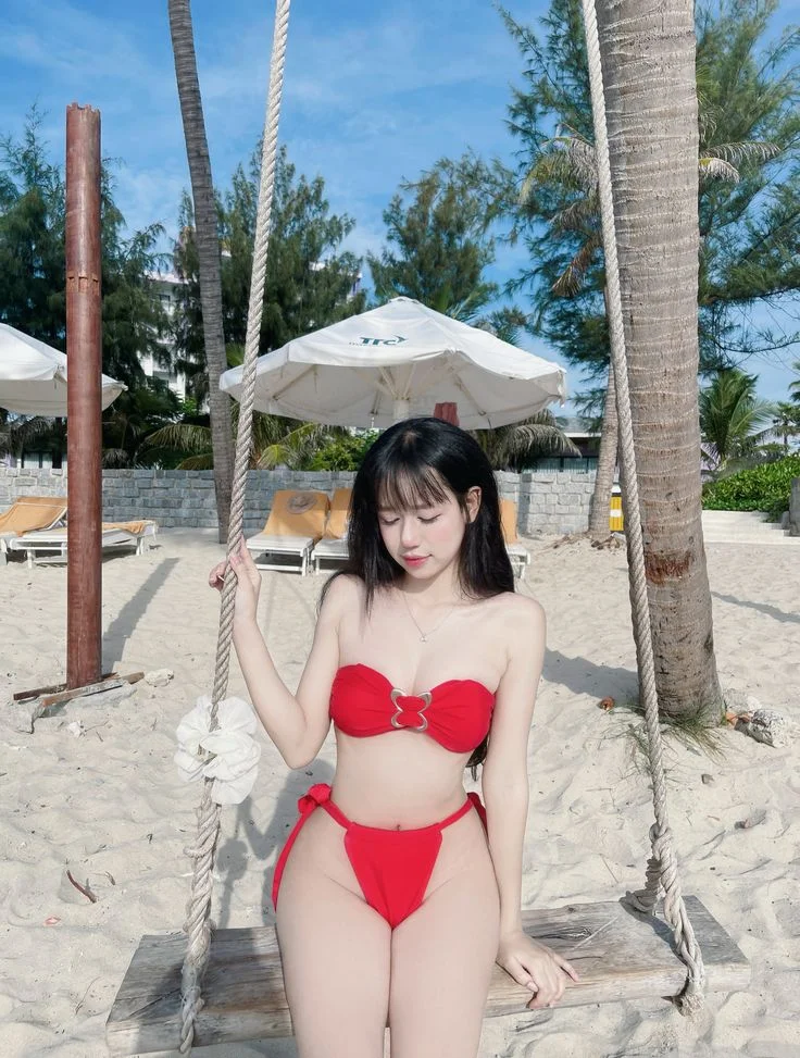 Gái xinh mặc bikini đỏ đi biển dưới tán ô
