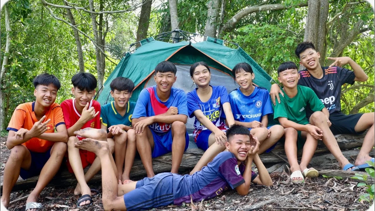 Nhóm bạn trẻ ngồi nghỉ ngơi bên lều trại trong rừng