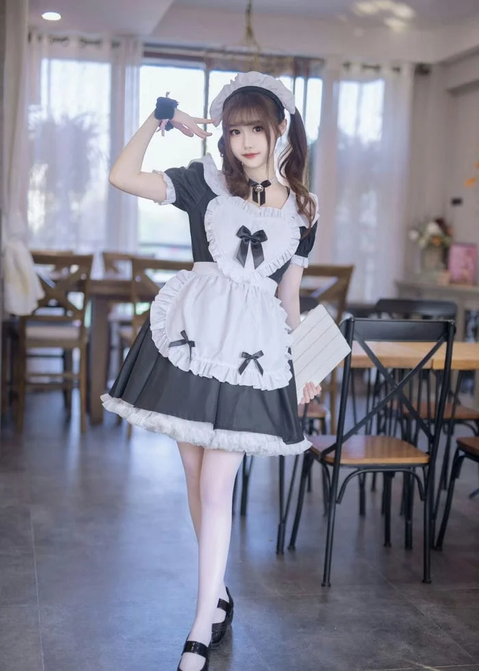 Cô gái trẻ trong trang phục cosplay hầu gái dễ thương tại quán cà phê