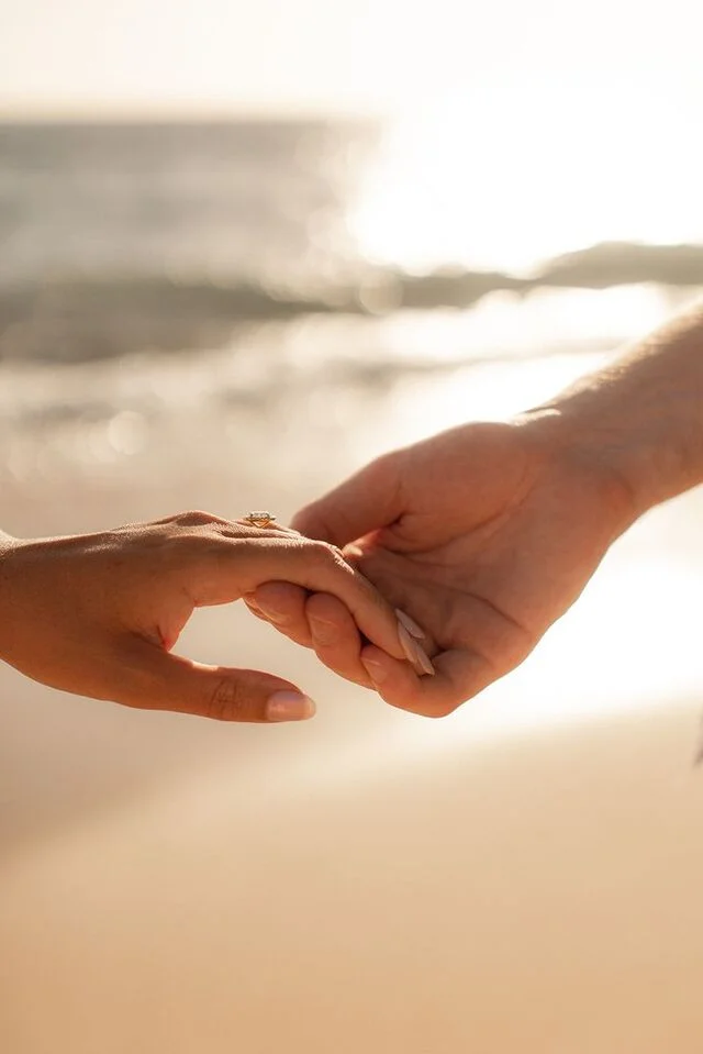 Ảnh nắm tay lãng mạn của cặp đôi trên bãi biển với chiếc nhẫn đính hôn nổi bật