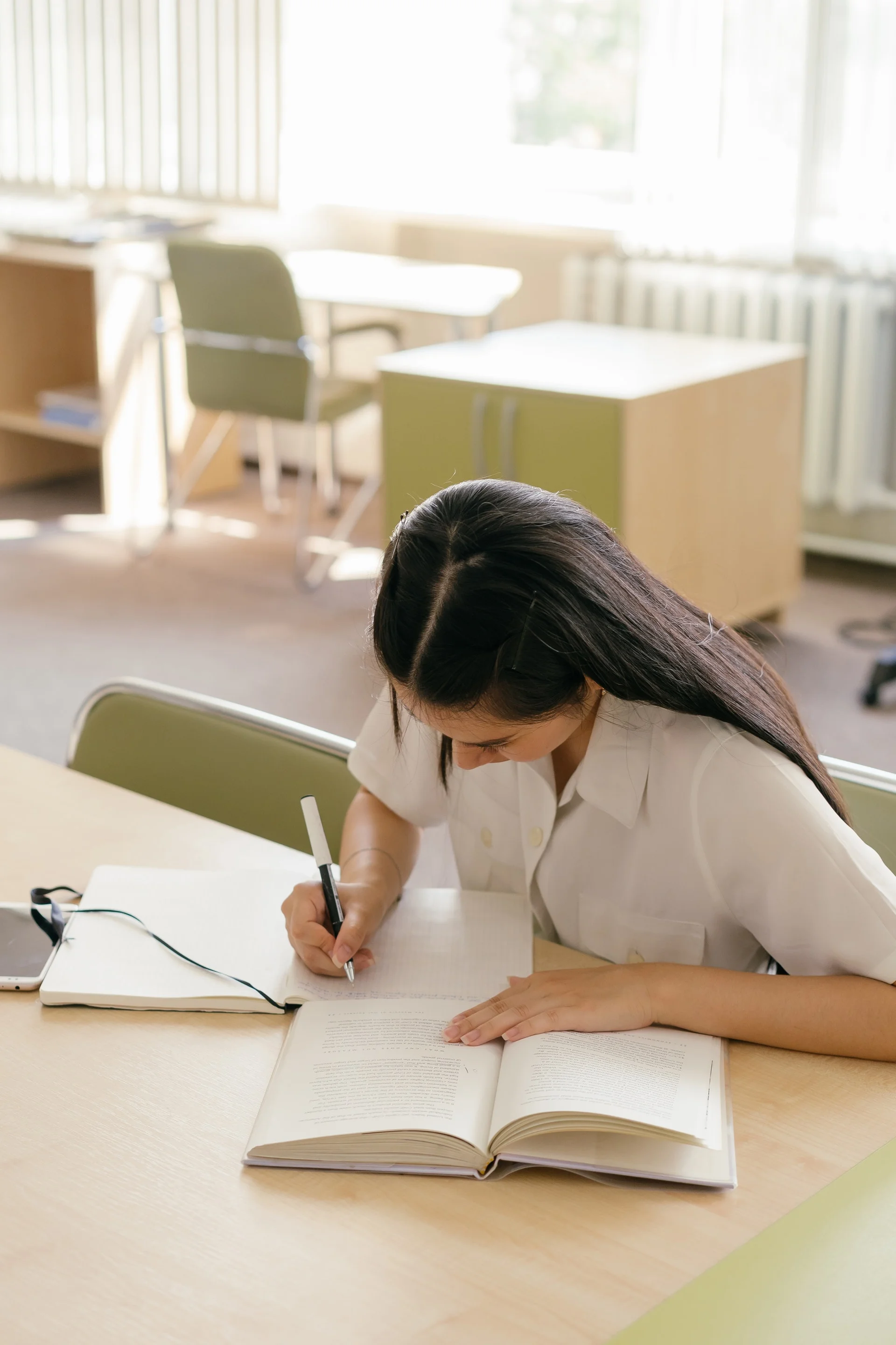 Nữ sinh đang chăm chú đọc sách và ghi chép trong ảnh học tập tại thư viện
